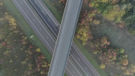 overhead drone shots of mountainbiker riding over overpass of the highway and nature