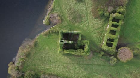 aerial view of overgrown castle ruins by a lake