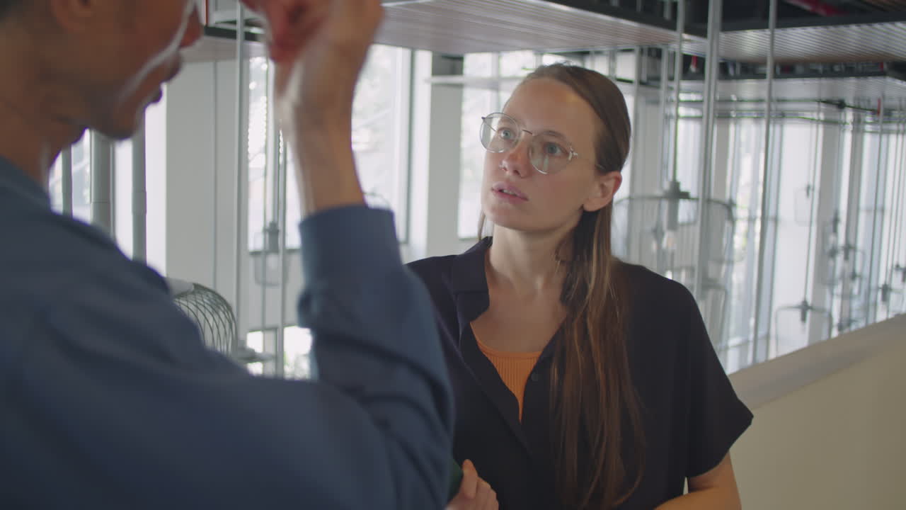 Young Woman Speaking with Coworker in Office Center