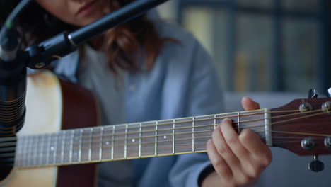 chica atractiva grabando el sonido de la guitarra con micrófono de condensador