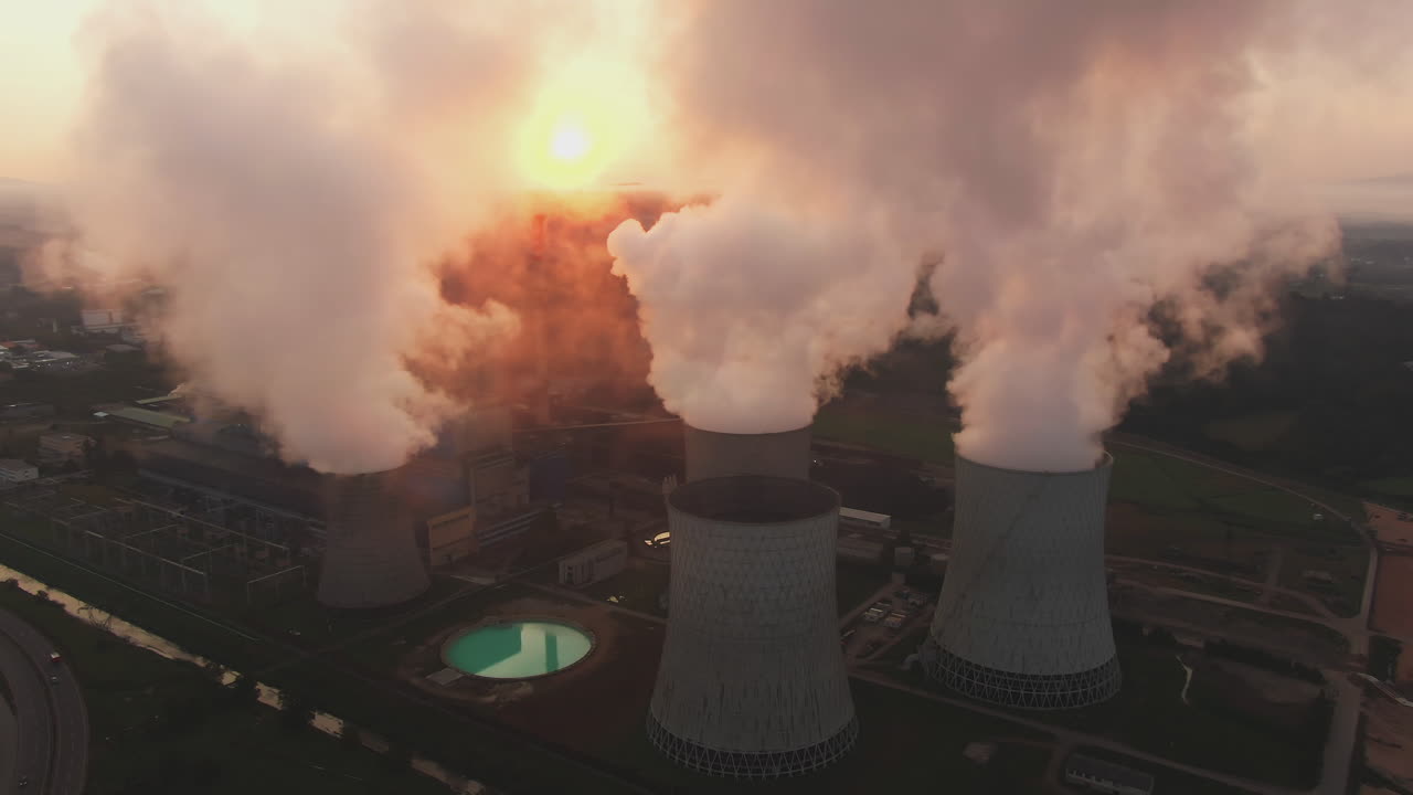 Aerial view of a coal power plant with smoke billowing from cooling towers
