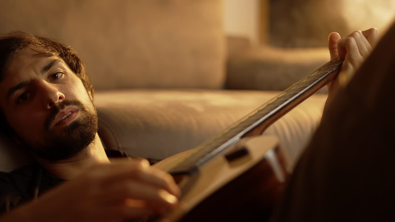 Trist mand spiller guitar, mens han sidder på gulvet i et røget lokale