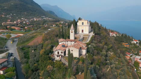 orbit shot of distinctive classic italian church on high-rise summit near mountains