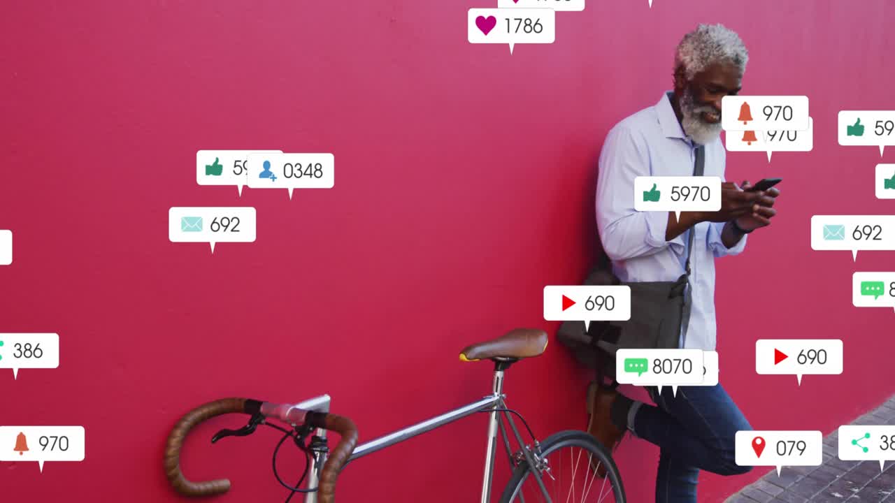 Kırmızı duvara yaslanmış adam, telefonunun kilidini açıyor ve bisikletin etrafında yüzen sosyal uyarıları kaydırıyor.