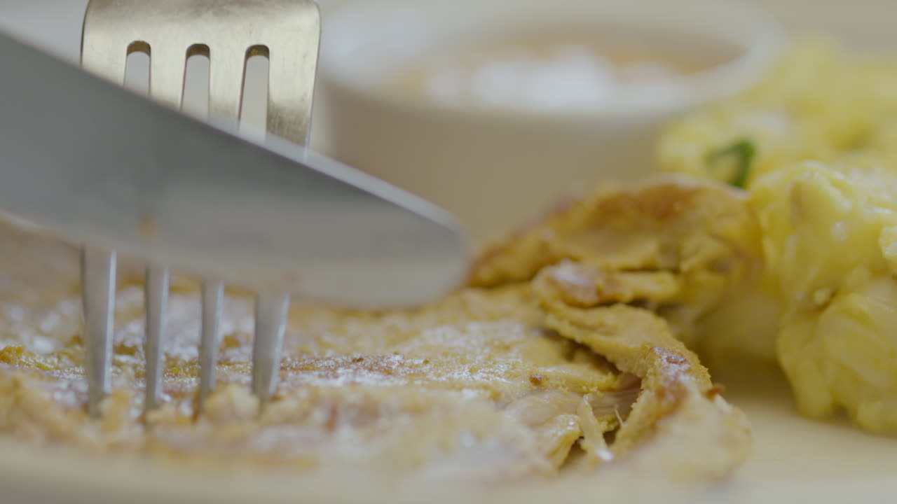 Close-up of a fork pressing tender meat accompanied by mote pillo and sauce