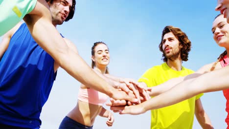 fit man and woman forming hand stack on the beach