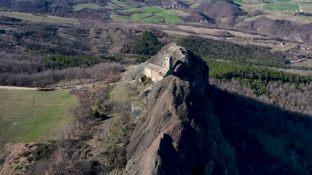 imágenes aéreas de pietra perduca, roca volcánica, iglesia situada en la piedra superior inmersa en el paisaje rural, tierra cultivada en val trebbia bobbio, emilia romagna, italia