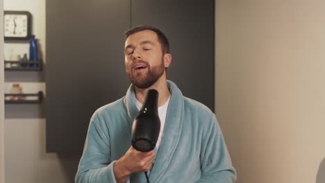 a cheerful man dries his hair with a hair dryer with joy on his face