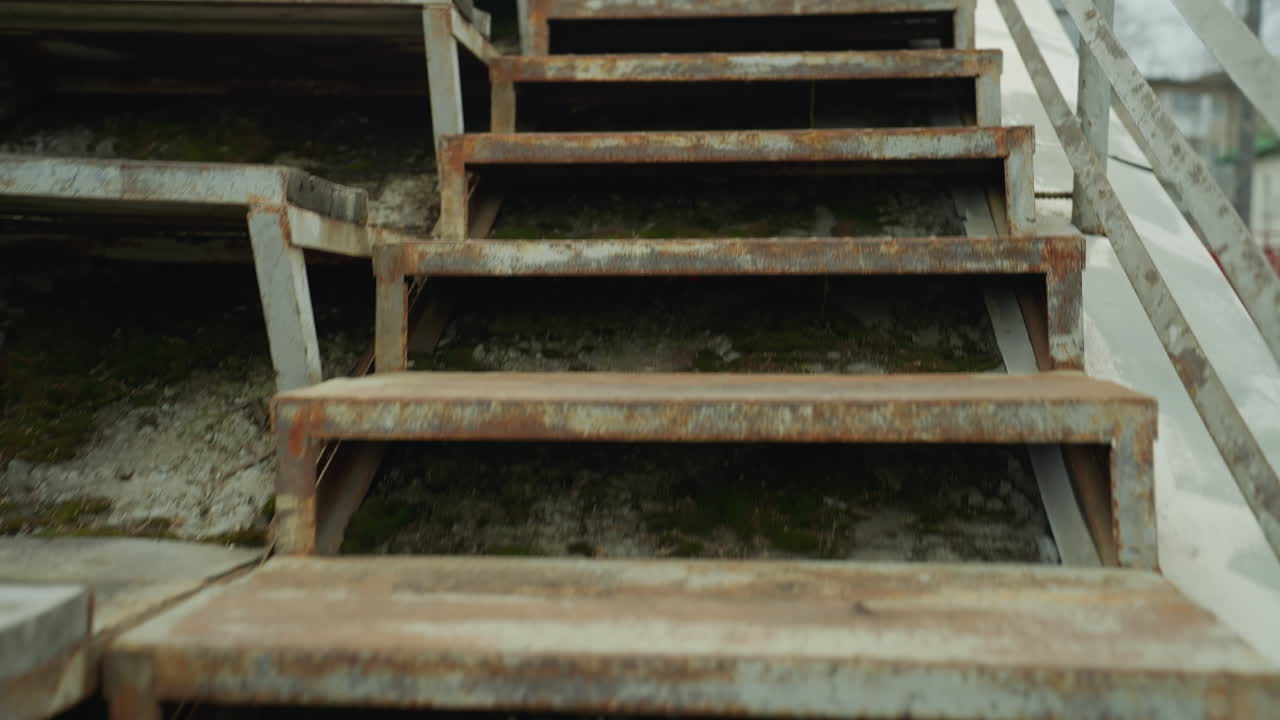 Close up leg view of someone jogging in front of a rusty staircase fast