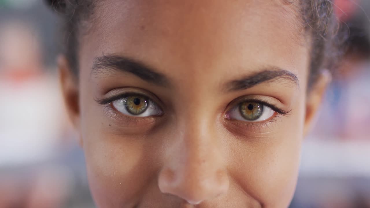 retrato de una estudiante biracial feliz en un escritorio en un aula escolar