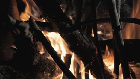 burning wood logs in slow motion, glowing embers in a moody bonfire setting