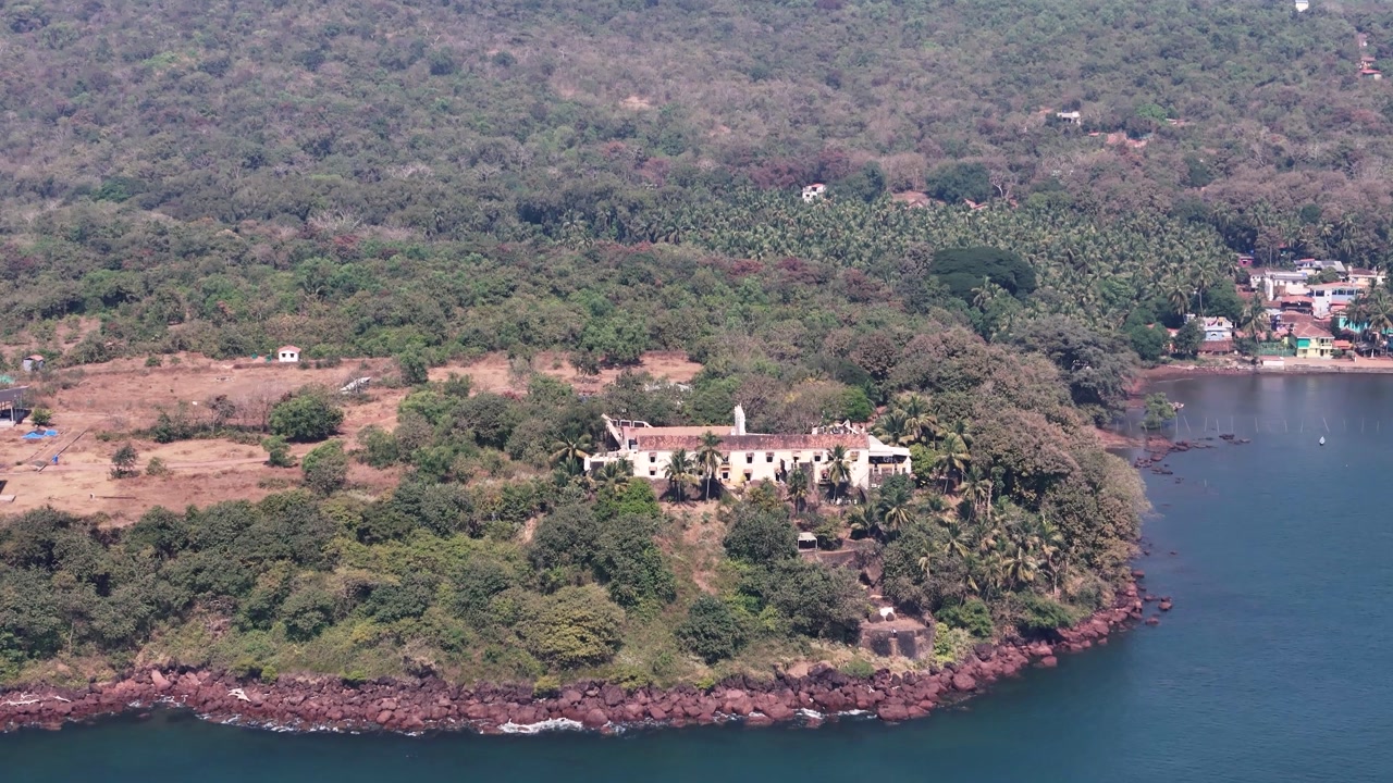 Aerial drone view of the historic Terekhol Fort, a heritage hotel on a coastal cliff at the northern tip of Goa, India.