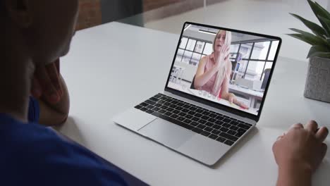 African-american-businesswoman-sitting-at-desk-using-laptop-having-video-call-with-female-colleague