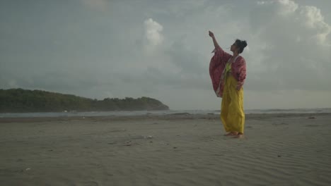 Indian-girl-and-yellow-outfit-flying-a-kite-on-a-beach-on-a-cloudy-day