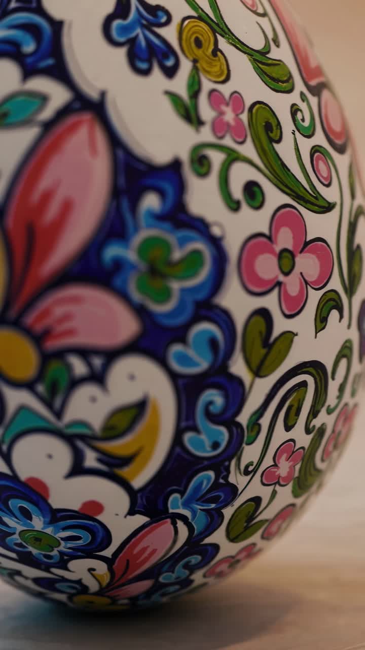 Detailed closeup showcases the vibrant floral pattern adorning a ceramic piece, its colorful design standing out against the warm tones of the wooden surface beneath
