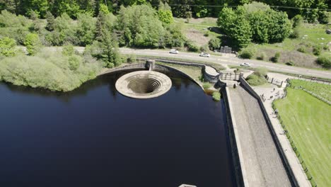 plug hole of ladybower reservoir in hope valley, derbyshire, england with vehicles passing by on the road