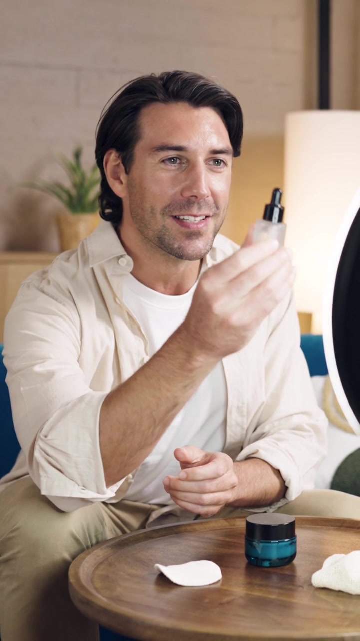 Man Demonstrating Skincare Products in Front of Ring Light