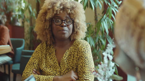 mujer de negocios afroamericana hablando con un colega en un café