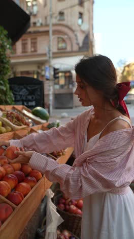 woman buying peaches at an outdoor market