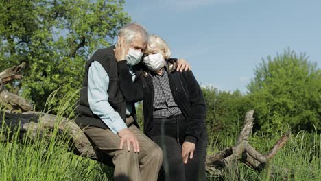 senior couple in medical masks during covid-19 coronavirus quarantine in park