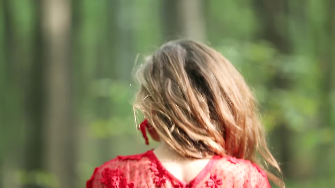 Beautiful Woman Walking Through Green Forest. Beautiful woman in red long dress walking through green forest
