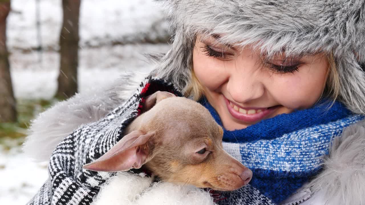 여자 는 겨울 밖 에서 작은 개 와 함께 놀고 있다