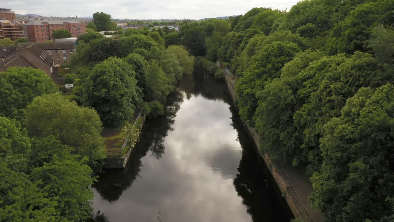 una toma suave de un dron que viaja por un río de la ciudad bordeado de árboles | el agua de leith, edimburgo, escocia | filmado en 4k a 30 fps