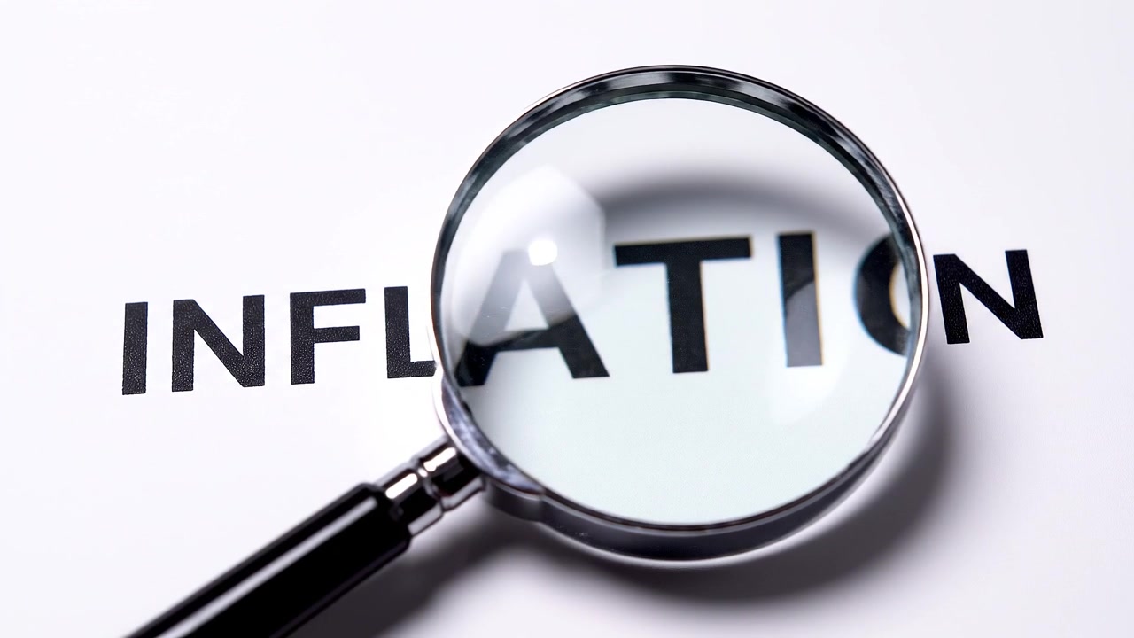 Magnifying glass examining the word inflation on white background
