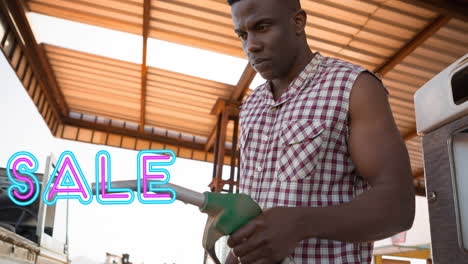 animation of sale text in neon over african american man using fuel pump at petrol station