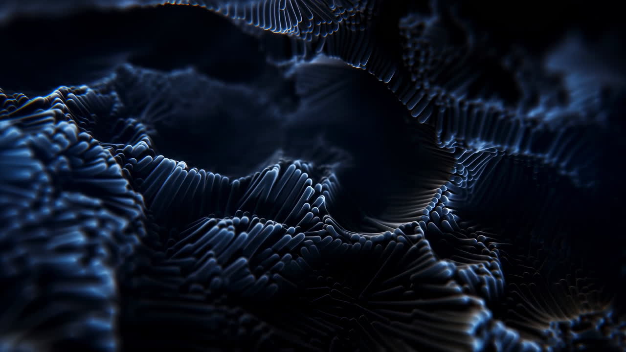 Paesaggio di particelle scure con topografia a creste, punti illuminati di blu formano creste fluide e onde superficiali granulari.