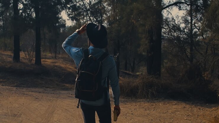 Uomo che cammina nel bosco con un libro in mano.
