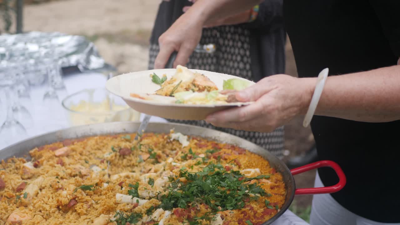 foto de una mujer sirviendo un hermoso plato de paella a otra persona