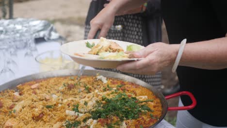 shot of a woman serving a beautiful paella dish to another person