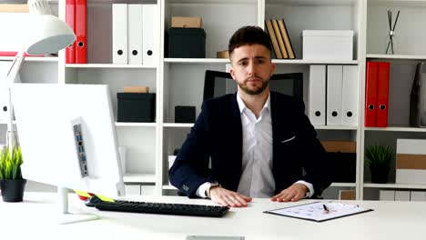 joven empresario haciendo un gesto con la mano y mirando a la cámara
