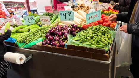 persona que selecciona verduras en el puesto del mercado