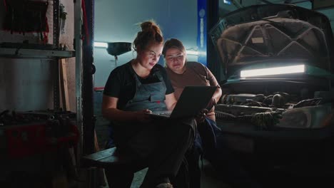 Women Mechanics Inspecting a Car with a Laptop