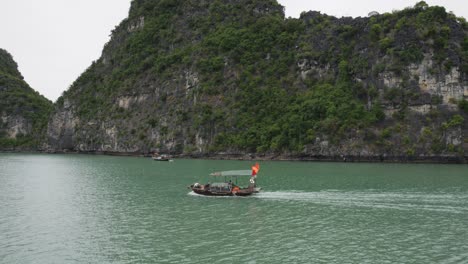 boat cruising in the ha long bay with limestone cliffs in the background in vietnam
