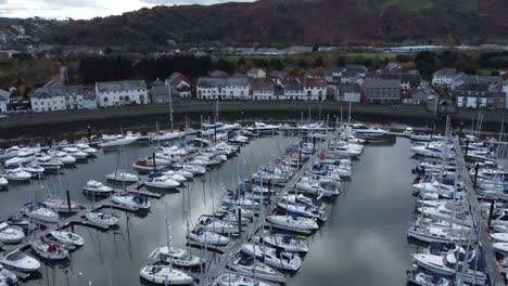 Scenic-luxurious-waterfront-harbour-apartment-village-yachts-and-sailboats-under-mountain-coastline-aerial-view-fast-left-orbit