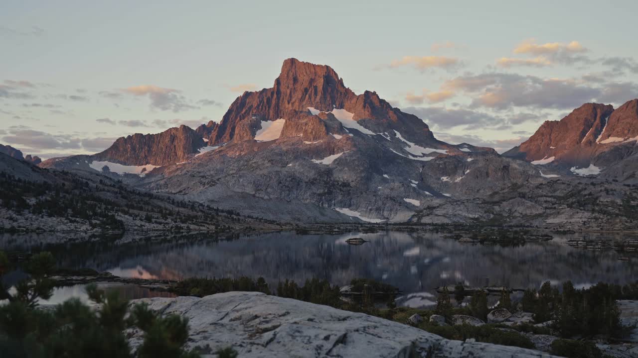 Mountain view at dusk along the John Muir Trail with rugged peaks, rocky foreground, and soft light
