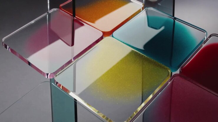 Tubi di vetro sospesi si inclinano, versando liquidi colorati in vassoi quadrati all'interno di uno studio, creando una griglia.