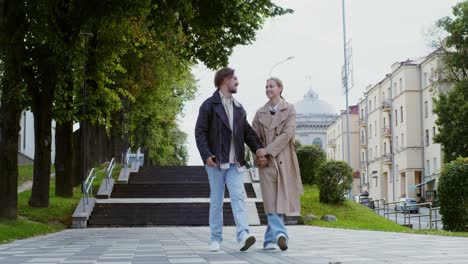 couple walking hand-in-hand in city park