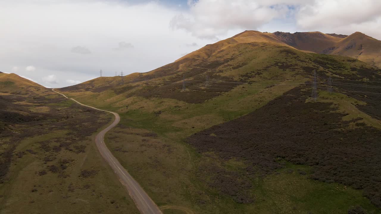 Discesa aerea verso una strada sterrata che attraversa montagne marrone-dorato.