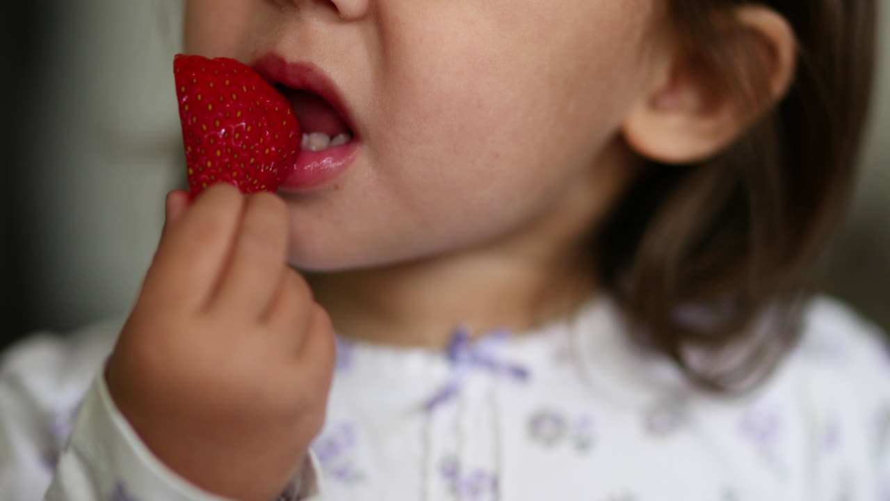 Toddler girl eating a strawberry