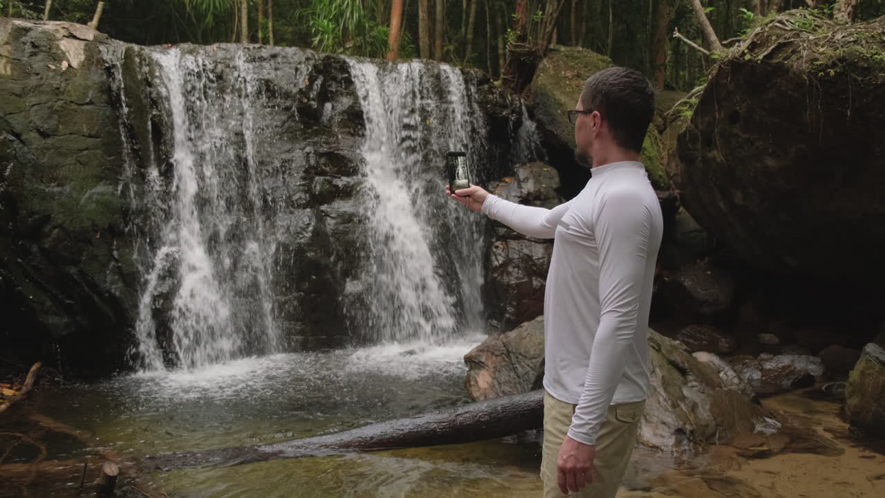 Man taking a selfie in front of a waterfall