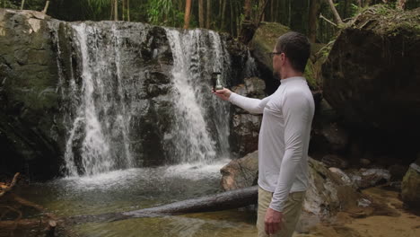 man taking a selfie in front of a waterfall
