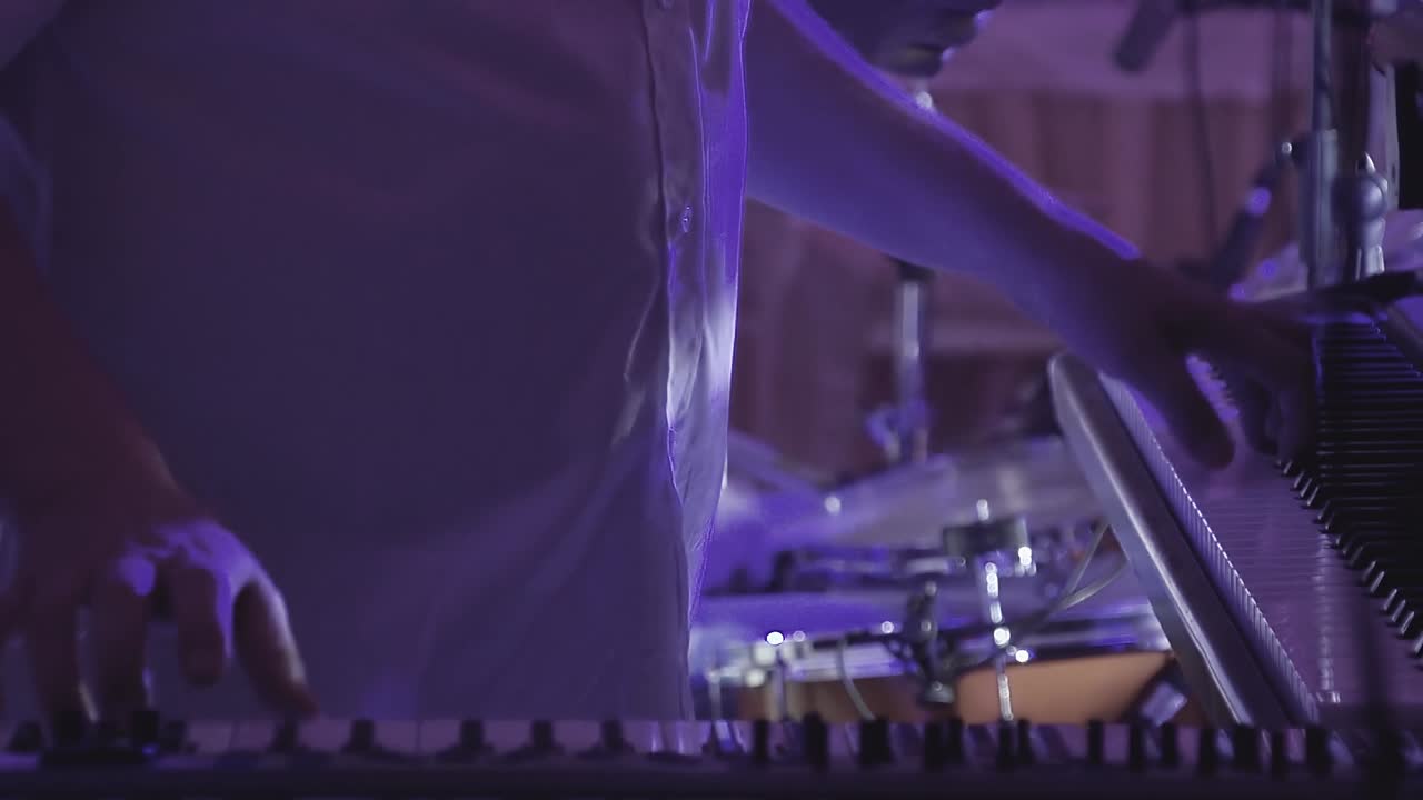 el tecladista toca varios instrumentos musicales en un concierto como parte de un grupo musical