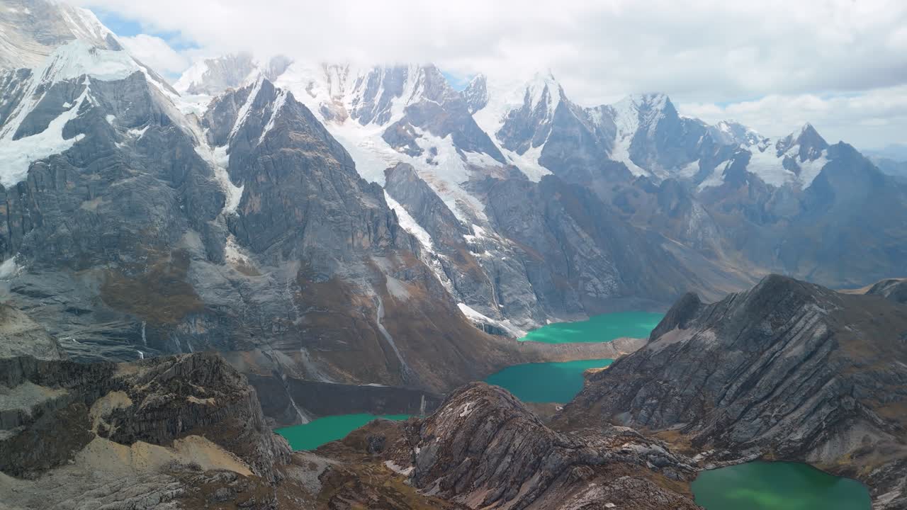 A breathtaking aerial reveal shot soars over the Andes to show the three famous turquoise glacial lakes Tres Lagunas of the remote and beautiful Huayhuash trek in Peru