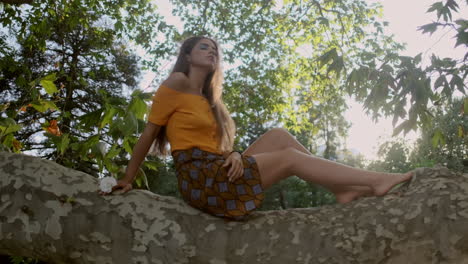 young girl model looking around sitting on tree branch