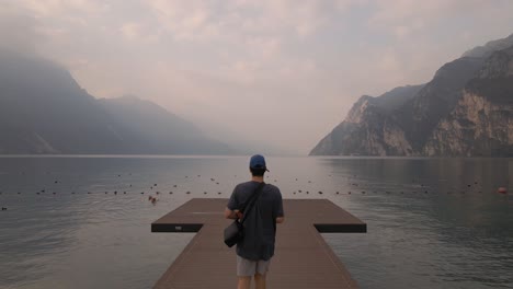 aerial view of man walking on wooden dock at scenic lake garda, northern italy