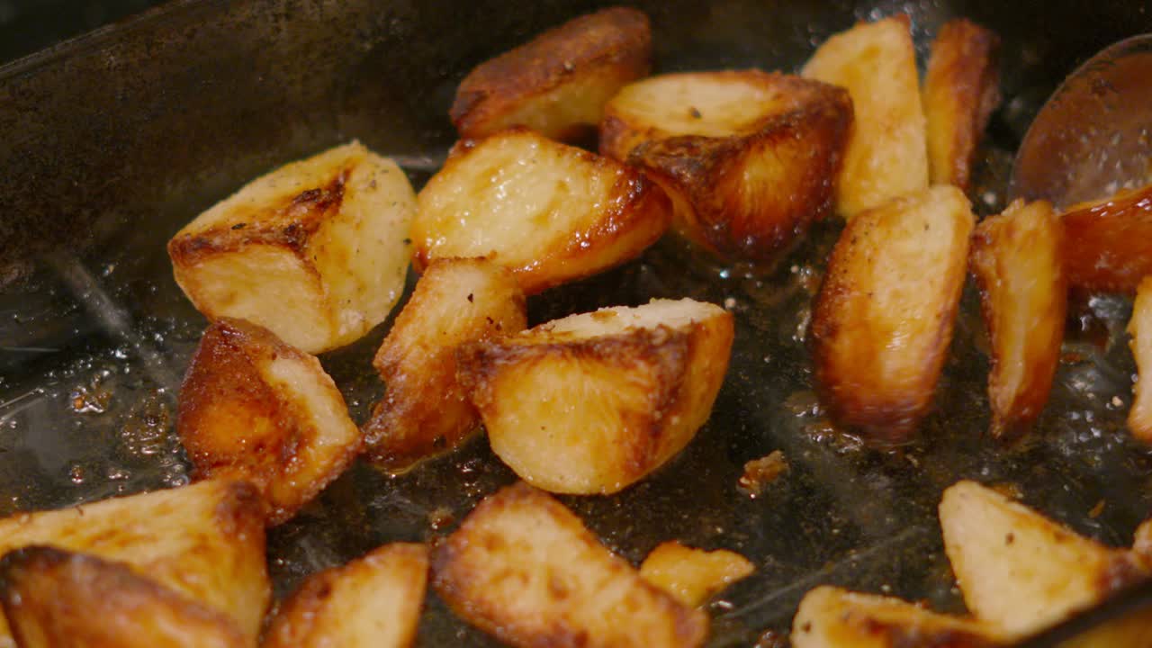 Freshly Cooked Roast Potatoes Being Turned and Flipped with Spoon in Slow Motion with Hot Oil 4K